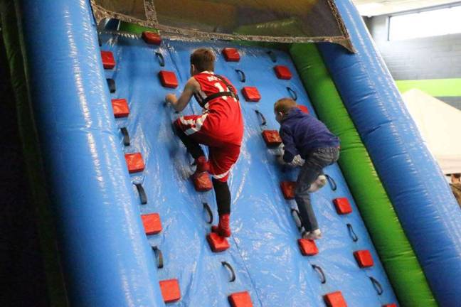 Boys are shown climbing the inflatable wall.