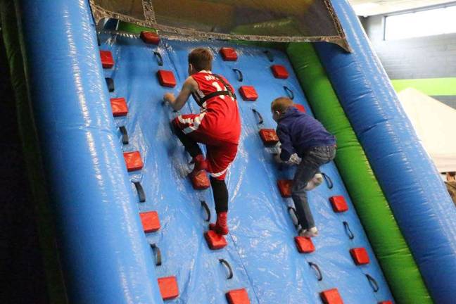 Christian Faith Fellowship holds family day Boys are shown climbing the inflatable wall.