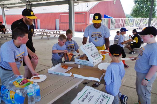 Sussex County Miners manager, Bobby Jones (center) along with staff and campers enjoy pizza during lunch.