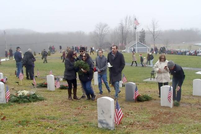 Family volunteers place wreaths and remember, honor and teach.