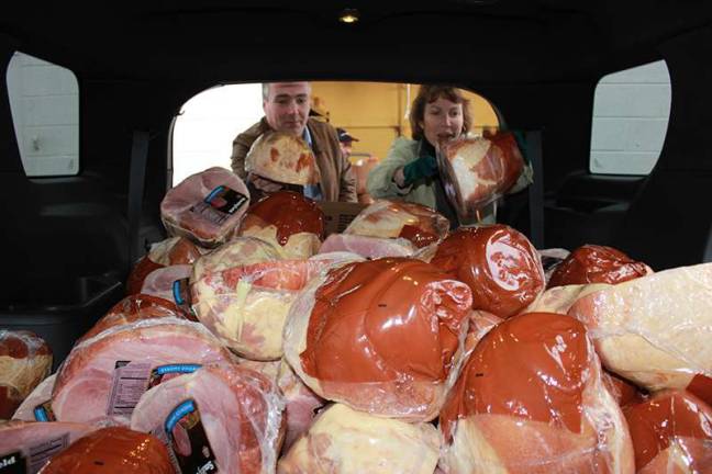 Labor Commissioner Harold J. Wirths and his wife, Debbie, load 125 Christmas hams outside the Weiss Supermarket in Franklin, Sussex County, for packaging with other goods and gifts for needy families.