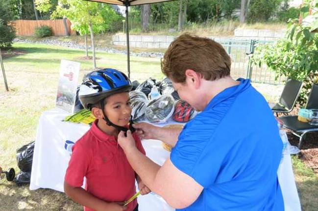 TransOptions, Cycle Craft distribute bikes at Project self Sufficiency Alesandro Barradas is fitted with a helmet provided by TransOptions and Cycle Craft.