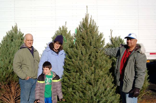 Ray Woody, Elijah Woody and Laura Woody selected this Christmas tree from a number of trees available at the Legion. Commander Mehandra Lakhicharran of Legion Post 423 stands ready to help deliver the tree.
