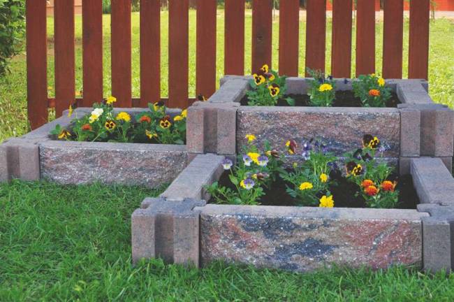 Courtesy of Infinity Lawn and Garden Incorporating raised flower beds using stone planters can beautify the landscape without taking a lot of time or effort.