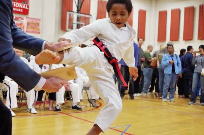 Seven year old martial artist Tade Adeyeri breaks a wood board with a leaping kick. Adeyeri won second place in the board breaking competition. Adeyeri represents DAYHAN Holistic Martial Arts of Leonia, N.J.