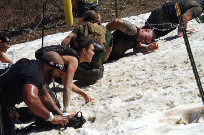 Races crawl up the snow-covered barbed wire section of the course.