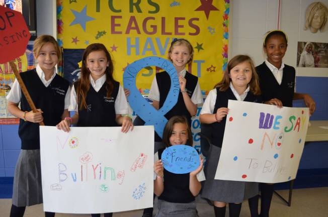 Immaculate Conception school has bully-buddies Fifth-grade students with their younger Bully Buddies show posters and signs to support anti-bullying before reciting their anti-bullying pledge.