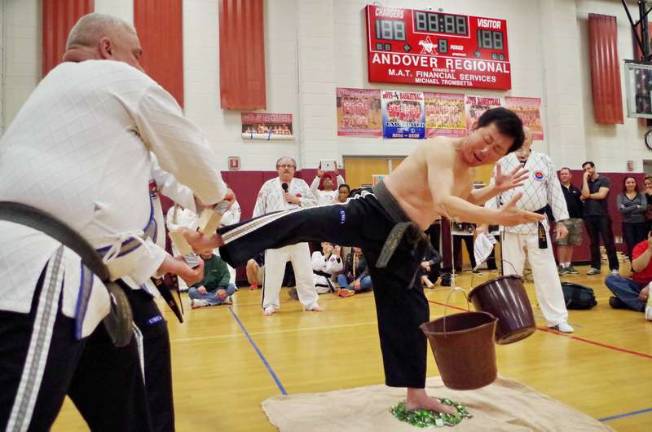 Martial Arts Mania in Sussex County Grandmaster Ik Hwan Kim shows physical and mental discipline while breakinig a board standing on broken glass with two buckets pinned to his forearms with metal pins. The pins go right through his flesh but he does not bleed. Kim is the owner of Universal Martial Arts Institute of Lafayette, N.J.