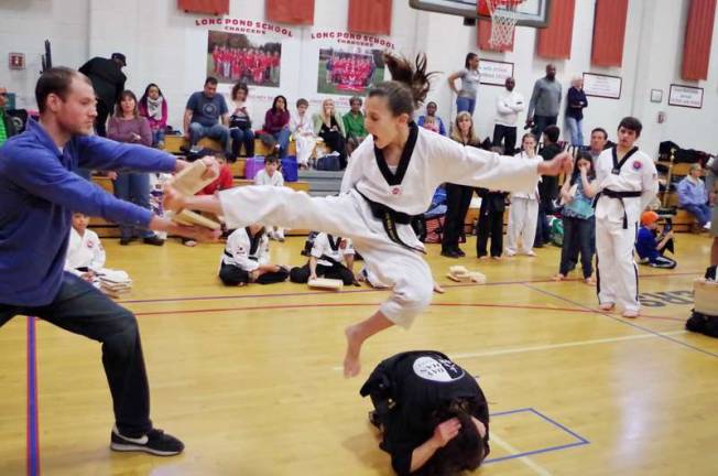 Eleven year old Grace Cuttone soars through the air during a leaping kick and breaks a wood board. She won second place in the board breaking competition. Cuttone represents DayHan Holistic Martial Arts of Leonia, N.J.