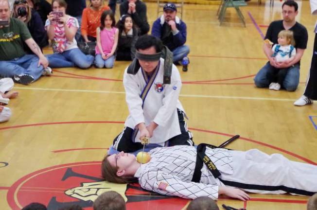 An apple is sliced by the sword welded by blindfolded Grandmaster Ik Hwan Kim without touching the neck of a fellow martial artist. Kim is the promoter and MC of the event.