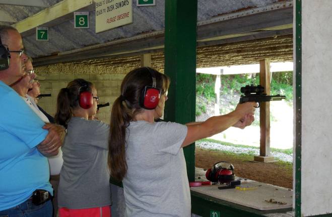 Shown taking careful aim at the target is student Claire Demetroules with her personal coach, Cliff Ryerson, making sure the fundamentals of safety and stance are followed.