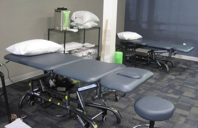 The therapy floor includes manipulation tables, exercise machines and weights.