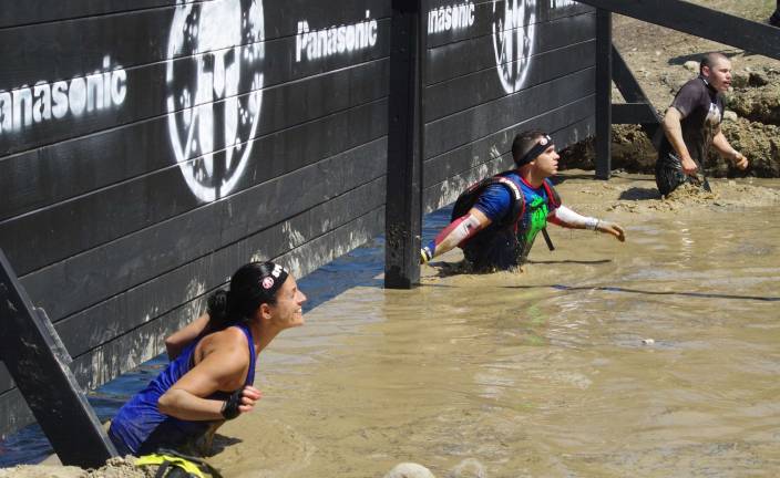 Racers make their way through the muddy water on their way to the snowy barbed wire crawl.