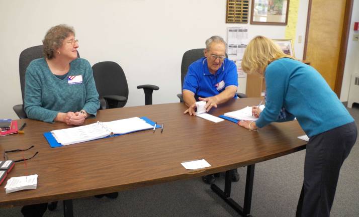 Photos by Chris Wyman Hamburg resident Wendy Brick is shown signing in to vote at the Hamburg Municipal Building. Seated are poll workers Linda Masson of Sussex and Jerry Reina of Hamburg.
