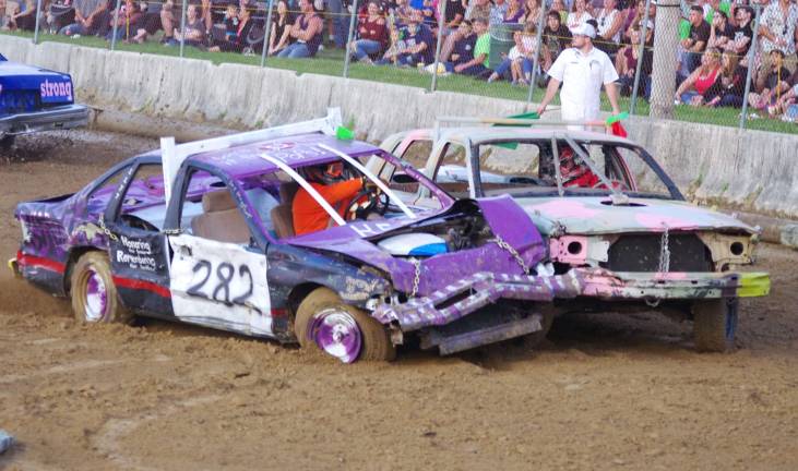 Cars bounce around at demolition derby Two competitors go head to head during a heat.