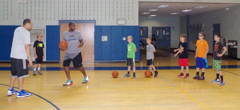 Basketball coach Cornell Thomas (holding ball) teaches camp participants.