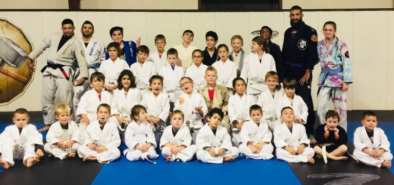 The Big and Little Spartans make wacky faces to celebrate following their teammates' promotions, along with four of their coaches including Black Belt Mike Pagano (Back row, left)