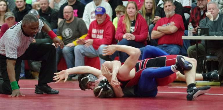 An official keeps close watch on wrestlers.