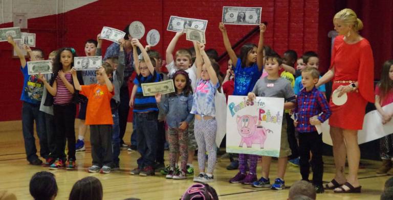 Students held oversized bills during the presentation of &quot;The Coin Challenge.&quot;