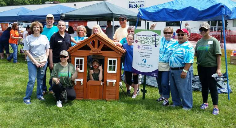 Lakeland Bank colleagues Deb Zimmerly, Nicholas Poulas, James Nigro, Jackie Turkington, Patricia Burroughs and her granddaughter, David Yanagisawa, Donna Orta and her husband stand with future homeowner Nathalie, active member of Army Reserves (far right) and kneeling is future homeowner Elena and her daughter Kelly (in playhouse).