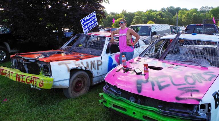 Demolition derby driver John LaFiura of Newton stands proudly between his cars.