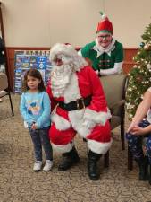 Ezra DeJesus stands by Santa, with elf Kathy Judd behind him. Santa arrived on a firetruck and greeted families inside the Hardyston municipal building. (Photos by Ava Lamorte)