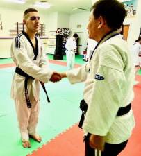Grandmaster Kim, president of the Universal Martial Arts Institute in Lafayette, congratulates John Fernandes, 27, of Sparta on his third-degree black belt in Taekwondo. (Photo by Laurie Gordon)