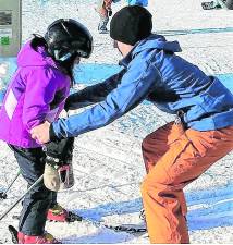 <b>Cory Gorczycki helps a child on the ski slopes.</b>