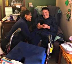 Continuum Healthcare employee Latoya Klein, left, helps resident Doris McGillick visit with loved ones virtually.