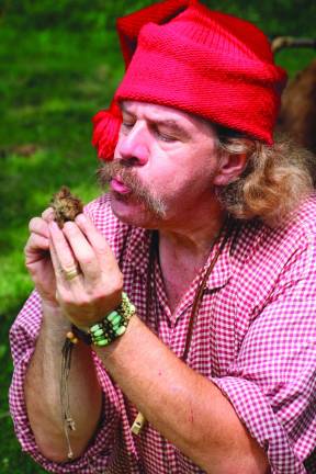 Fred Schofer of Lafayette &amp; Millbrook Village Society blows on some rope fibers to start a fire using only a flint stone.