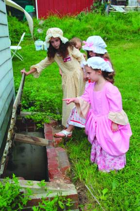 Emma Cooper gives a tour of the outhouse and where it gets cleaned out later.