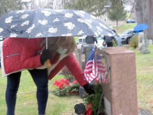 Ann Larsen places a wreath on her dad’s grave, an Army veteran of the Korean War (Photo by Janet Redyke)