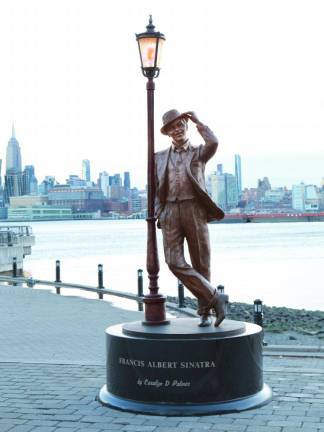 Carolyn Palmer’s statute has Sinatra leaning casually against a lamppost, facing Hoboken, with the New York skyline as a backdrop. The perpetually lit lamppost was also created by Palmer. The light casts an orange glow, which Palmer said was his favorite color and made him feel happy. A river breeze “lifts” his jacket. Every inch of his body exudes classic Sinatra cool: the casually crossed legs, the tilt of his head and the tip of his hat toward Hoboken.