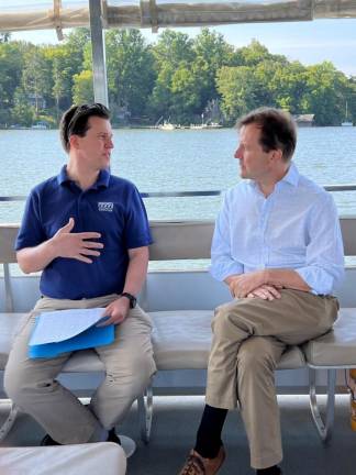 Alan Hunt, left, Musconetcong Watershed Association director, policy and grants, talks to Rep. Tom Kean Jr. about projects funded through the Delaware Watershed Conservation Fund during a boat tour of Lake Hopatcong. (Photo provided)