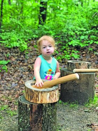 Zoë Smith of Hewitt poses by a tool used to mash corn in the Native Lenape Woodland Forest exhibit.