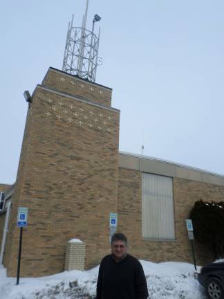 Anthony Selimo, founder of the Sussex County Community College radio station, stands in front of the E building where the radio station's two antennas stand. The taller one, at 49 feet, will broadcast the FM signal. Photo by Nathan Mayberg.