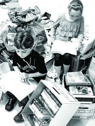 Emma Cahill, 11 and her brother Patrick Cahill, 6, both of Sussex, peruse over the mounting donations for the Friends of the Sussex-Wantage Library Fall Used Book Sale.