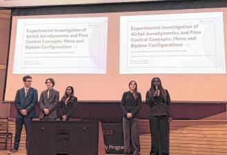 Samuel Tobachnick stands on stage with other students.