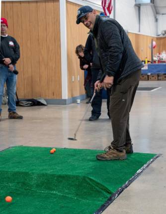 Ed Thomas takes part in the putting contest indoors.