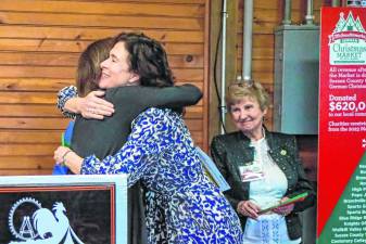 Maureen Dykstra, center, of Girls on the Run hugs Dawnice Lafave, who was handing out grants. At right is Karin Meyer, a trustee emeritus and co-founder of the German Christmas Market. (Photo by Brielle Kehl)