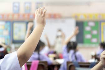 An example of children raising their hands in a classroom.