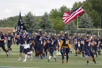 The Pope John Lions run onto the field carrying their team flag and the American flag just before the start of the game. Photos by George Leroy Hunter