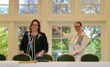 Madam State Regent Diane Waugh Oliver, left, is saluted by Laura Franek, Chinkchewunska chapter member and personal page to the state regent.