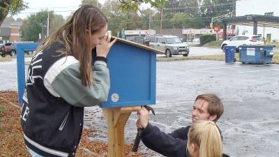 Riley Cunniffe, John Spadora and Danielle Fetzner assemble the Little Free Library.