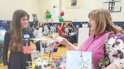 Antonia sells one of her hand-painted items to Terry Flynn.