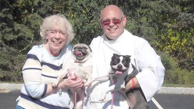 Christine Benson is shown with Molly (boston terrier and Maggie (pug) and Rev, Michael Rodak.