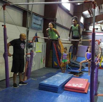 Twelve year old Cassandra Sullivan of Sparta Township and 10-year-old Micah Pryor of West Orange practice on the uneven bars.