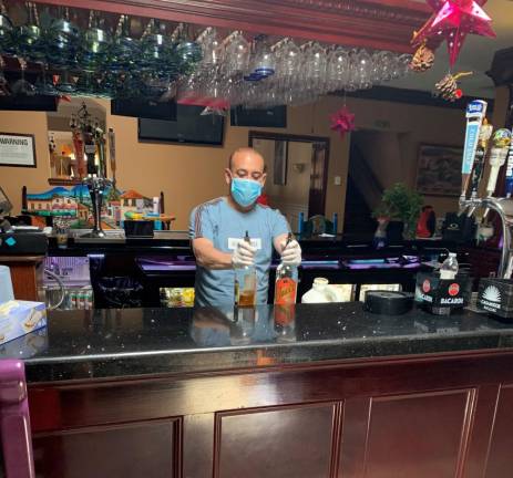 Hacienda’s bartender prepares drinks to go in an empty bar.
