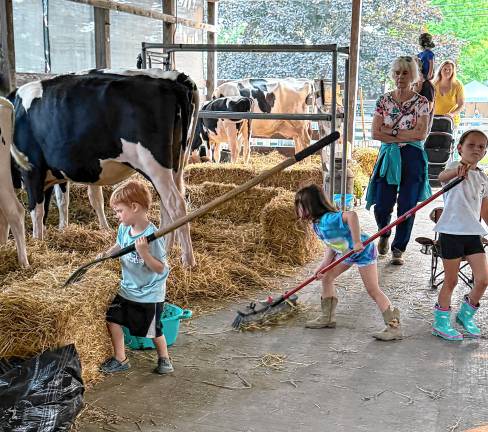 <b>Children help clean up after the cows Tuesday, Aug. 5. (Photo by Denise von Wilke)</b>