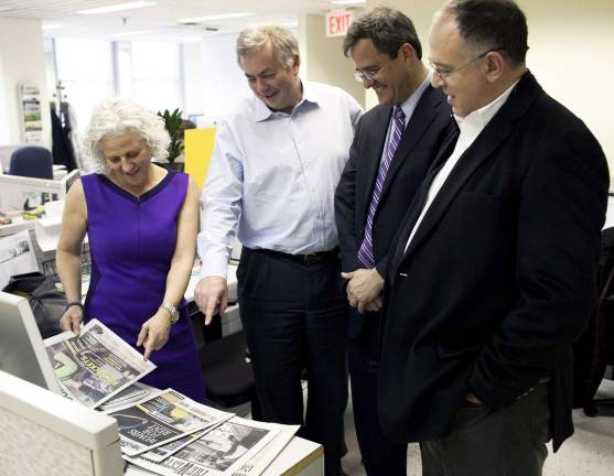 Photo by Aaron Adler/Manhattan Media Jeanne Straus, president of Straus News, looks over issues of her company's newly acquired New York City weeklies with William Pecover, Tom Allon and Richard Burns of Manhattan Media.